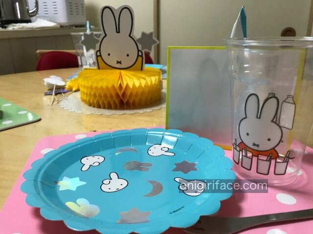 ダイソーミッフィーグッズ「ハニカムボール(置くタイプ)、紙皿、コップ」を机の上に置き、誕生日パーティーに準備中
